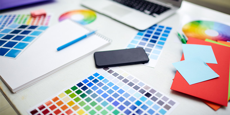 Materiales creativos sobre un escritorio. Hay elementos como: dispositivos tecnológicos, post it, cuadernos y colores.