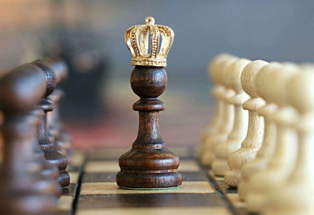 Peón con corona sobre tablero de ajedrez en medio de las demás piezas