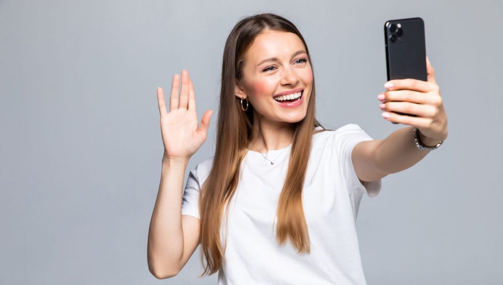 Una mujer sonriendo mientras tiene el celular en la mano.